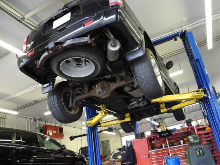 Automobile sollevata su ponte idraulico all’interno di un’officina meccanica durante controlli e manutenzione.