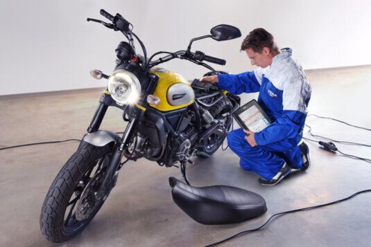 Tecnico che esegue diagnosi elettronica su moto con strumento diagnostico presso officina Brognoli Moto a Brescia